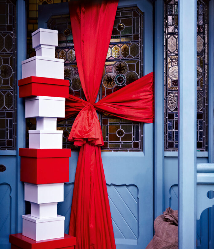 Blue front door wrapped in red ribbon