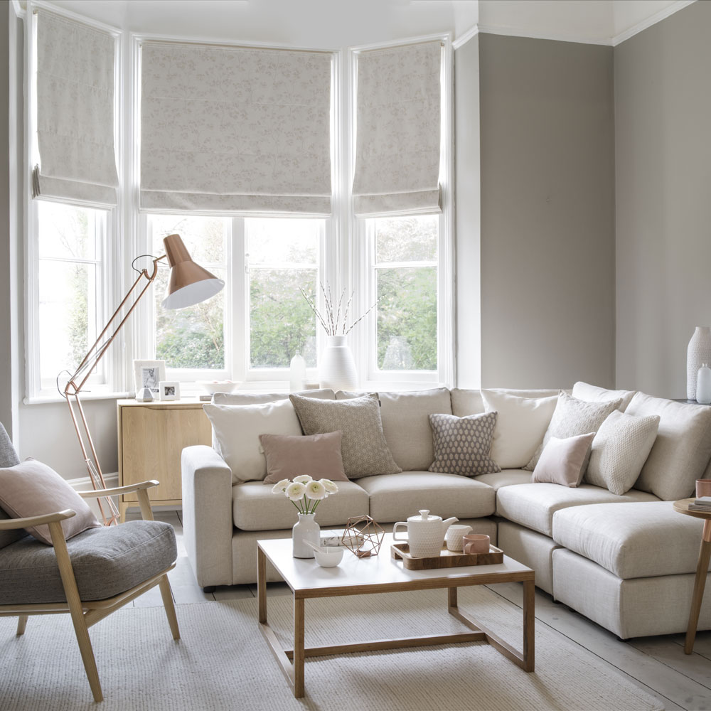 Neutral living room with comfy corner sofa floor lamp wooden armchair and coffee table