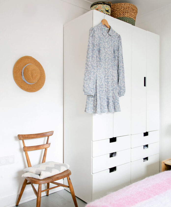 bedroom wardrobe with storage baskets on top and chair beside