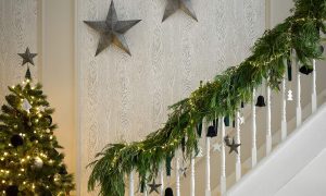 Neutral staircase with star decorations, garland and Christmas tree
