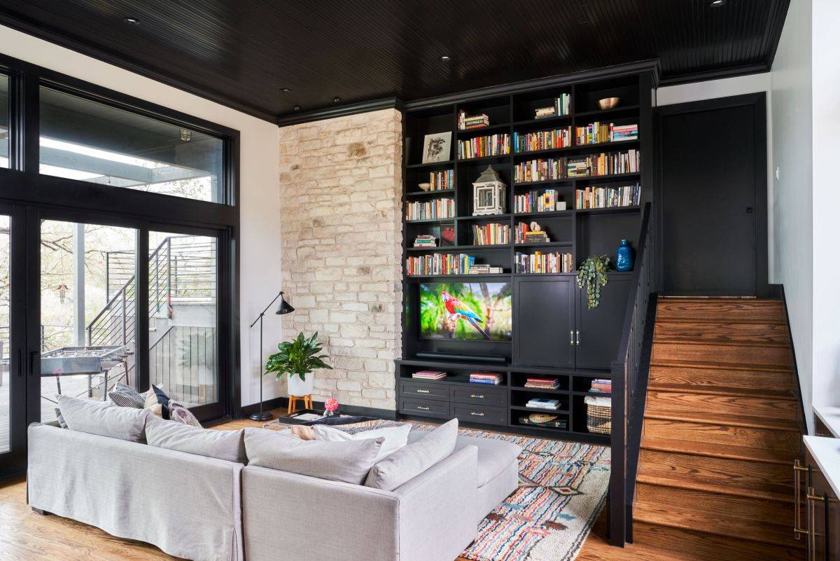 Entertainment wall coupled with bookshelves and exposed brick wall section in the stylish family room