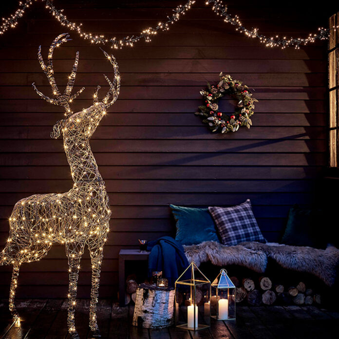 Black wooden clad house exterior with light up deer and light up garland