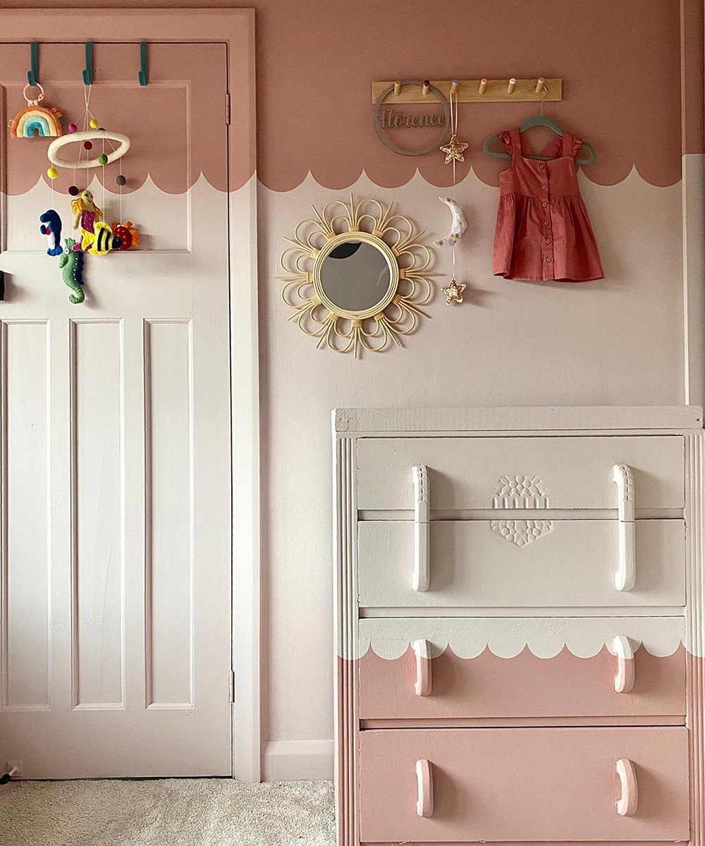 Kids bedroom with cream and pink scalloped painted wall, painted chest of drawers and rattan mirror