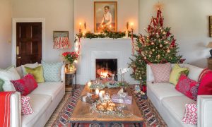 Living room with two cream sofas, wooden coffee table, fireplace, garland, candles and Christmas tree