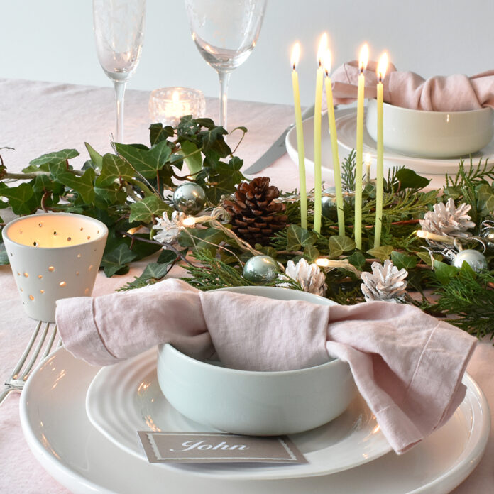 Pink linen knotted napkin on white tableware with pink linen tablecloth and foliage garland