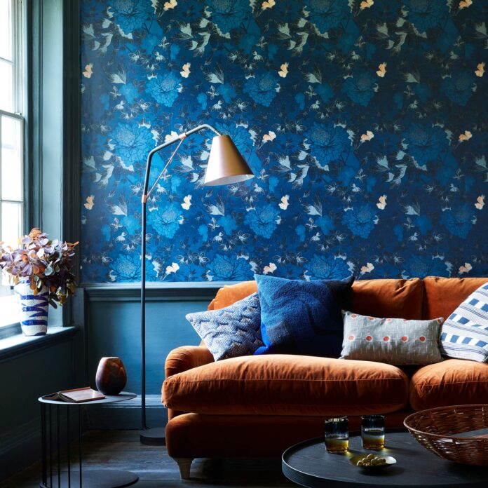 Living room with blue patterned wallpaper, orange sofa and brass lamp