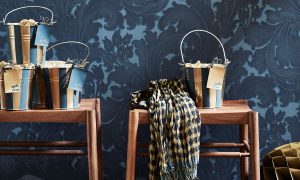 Metallic buckets on wooden benches in front of blue wallpaper