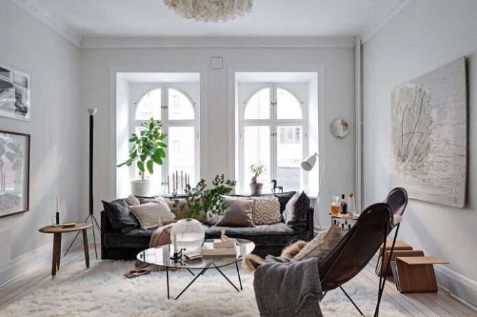 bright Scandinavian living room with large windows white walls black sofa leather armchair and plants 