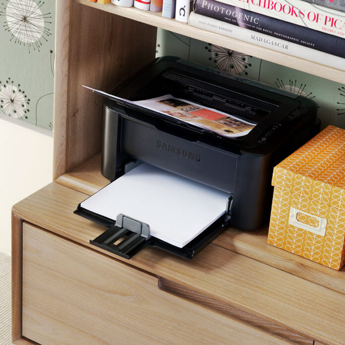 A close up shot of a black printer on a wooden unit