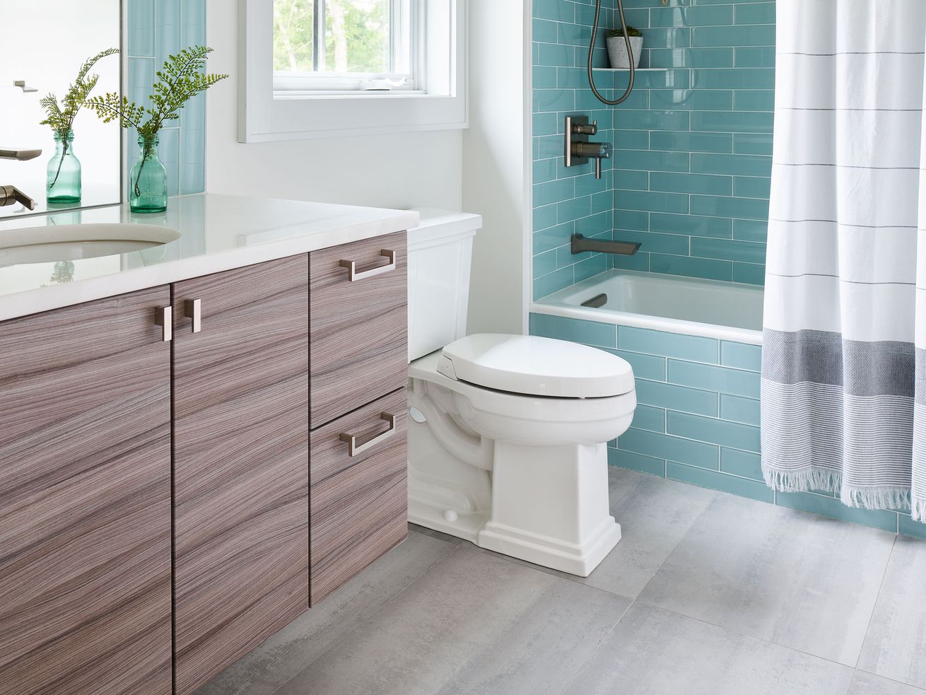 A bathroom with a floating vanity and a blue subway tile shower.