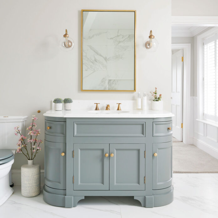 neutral bathroom with grey sink vanity until gold mirror above and wall lights either side