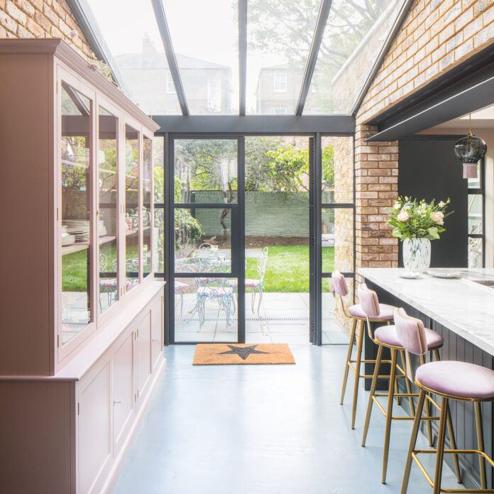 Kitchen extension with sky light, pink cabinet and pink bar stools at island