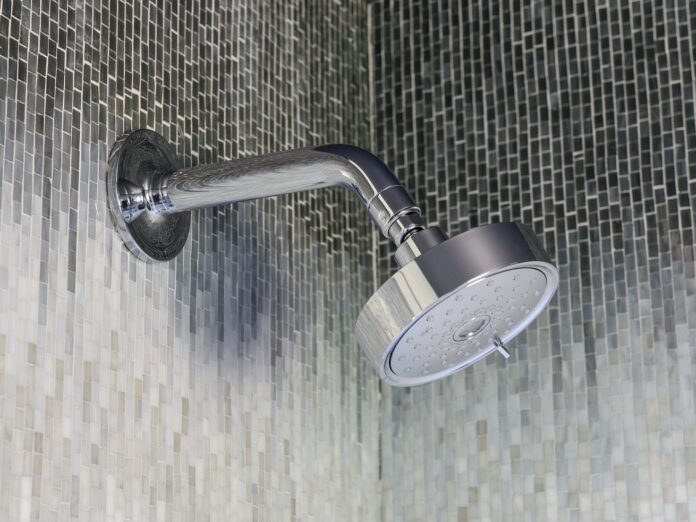 A clean silver shower head in a mosaic shower.