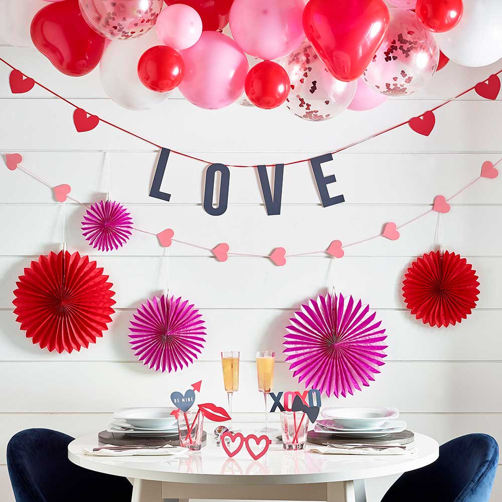 white dining table with champagne glasses, selfie proper and Valentine's decorations bunting and balloons