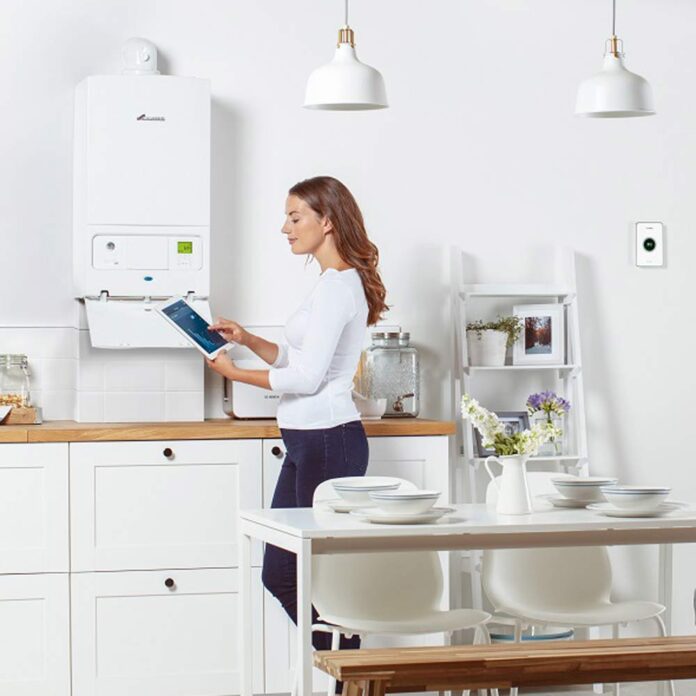 Woman with boiler and ipad in white kitchen