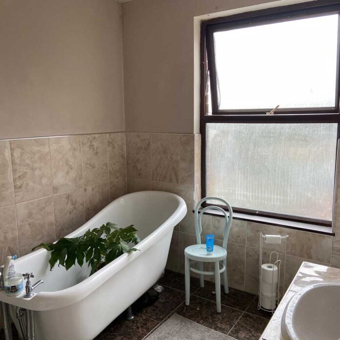 beige bathroom with white tub and large window