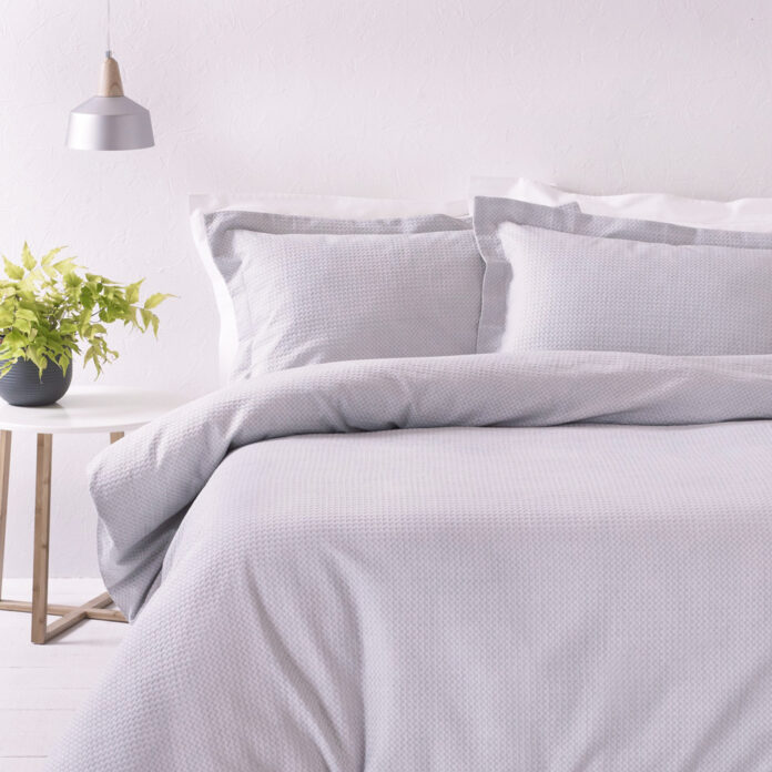 lilac grey bedding on double bed with light and side table