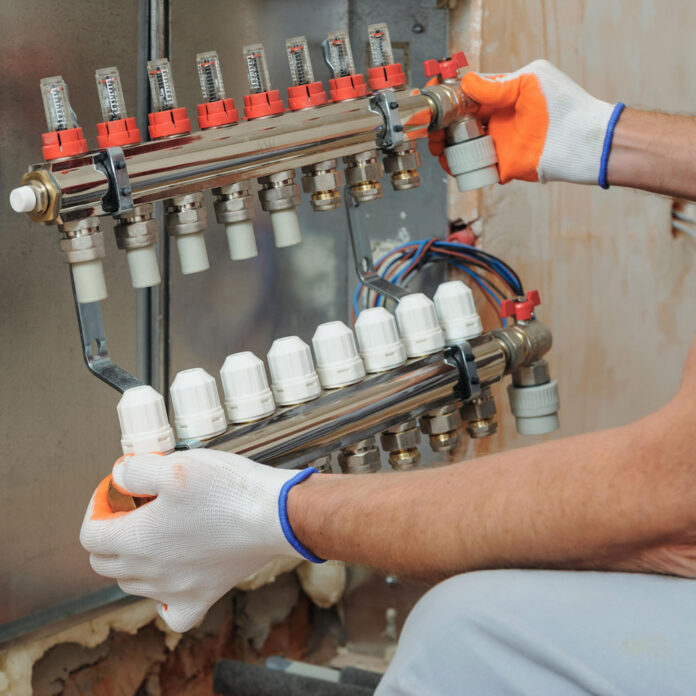 worker installing manifold for underfloor heating