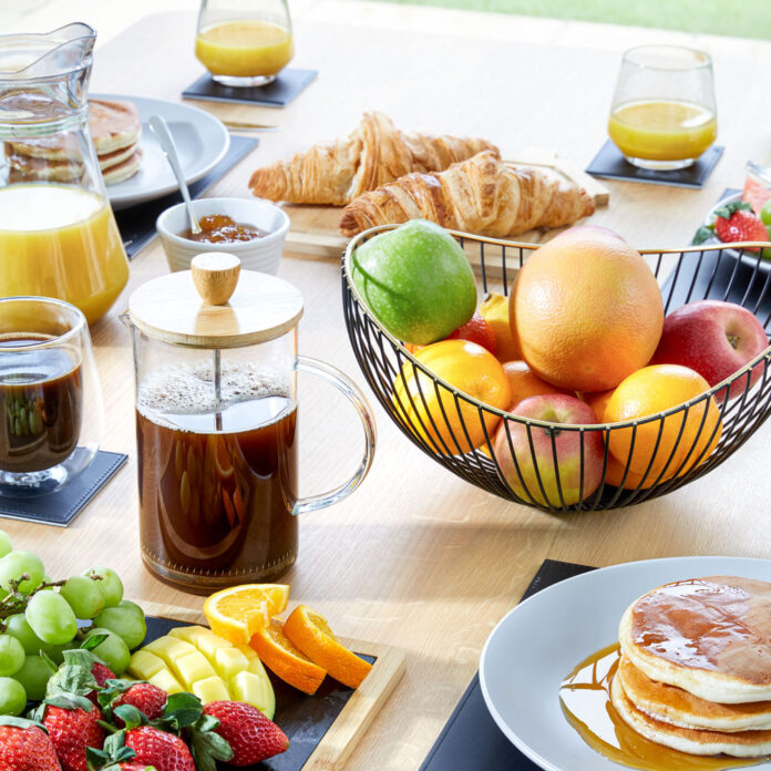 breakfast table laid with fruit bowl, coffee and pancakes