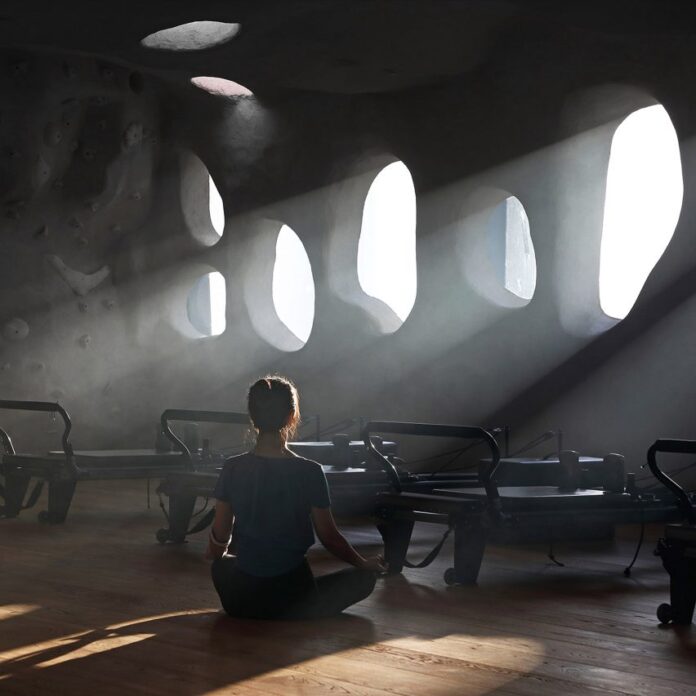 Woman sitting crosslegged on floor of T.T. Pilates studio in Xiamen by Wanmu Shazi with light streaming in through rounded windows