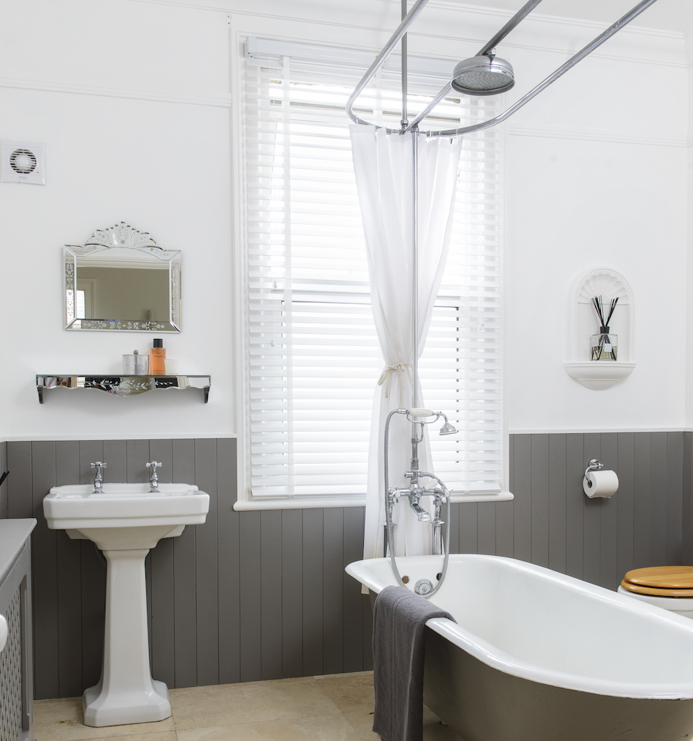 white and grey bathroom with wood panelling with shower over freestanding bath
