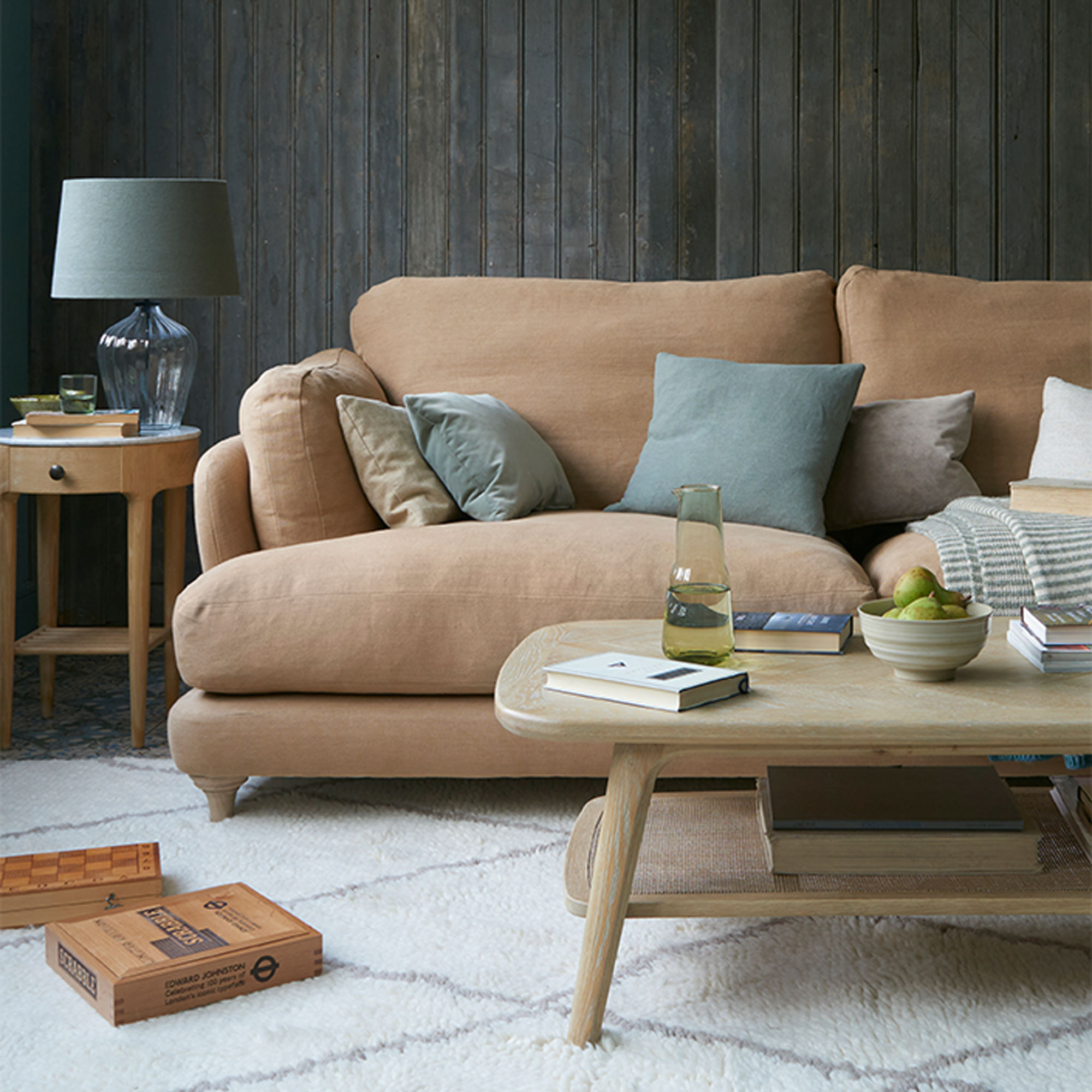 Brown linen sofa with dark wood panelling and berber rug