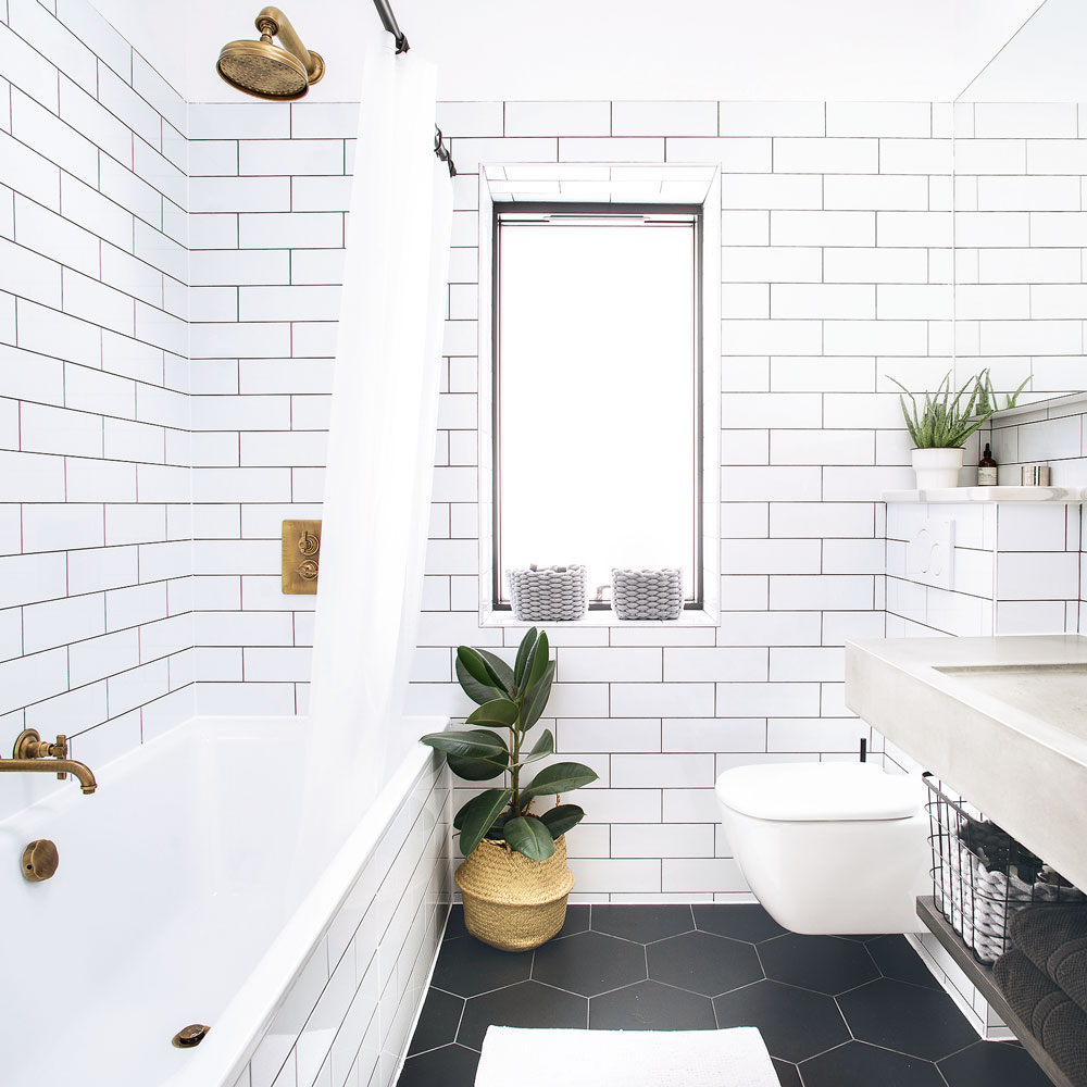Bathroom with white metro tiles on all walls black floor tiles and brass taps