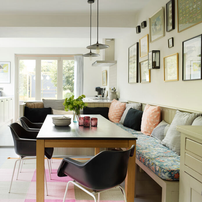 Kitchen with chairs and booth around table below pendants and gallery wall