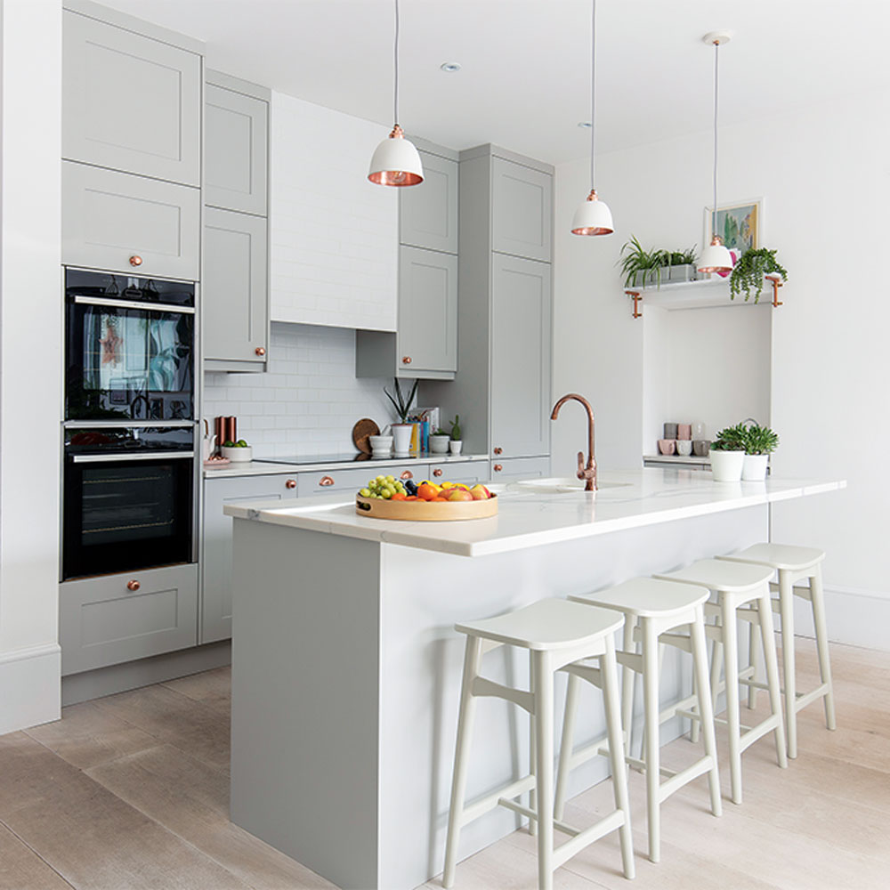 Grey kitchen island with grey bar stools and white and copper pendant lights