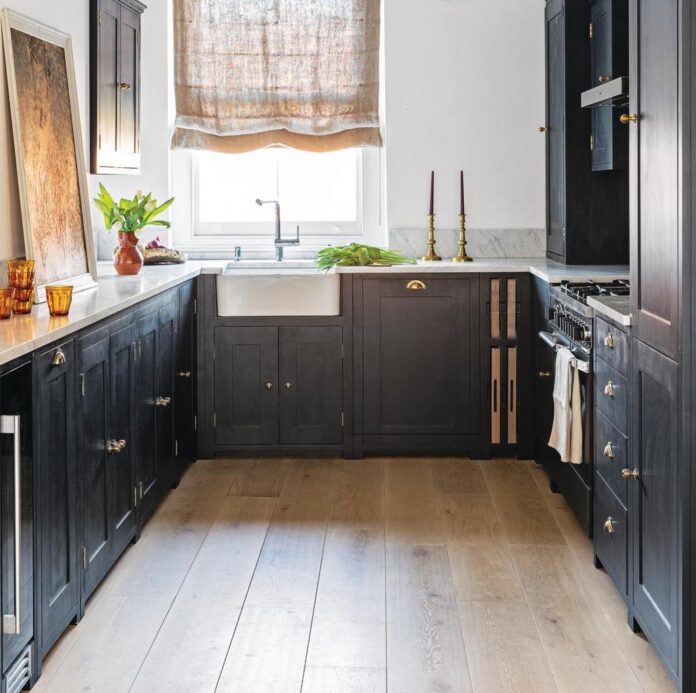 black kitchen with white walls and wooden flooring