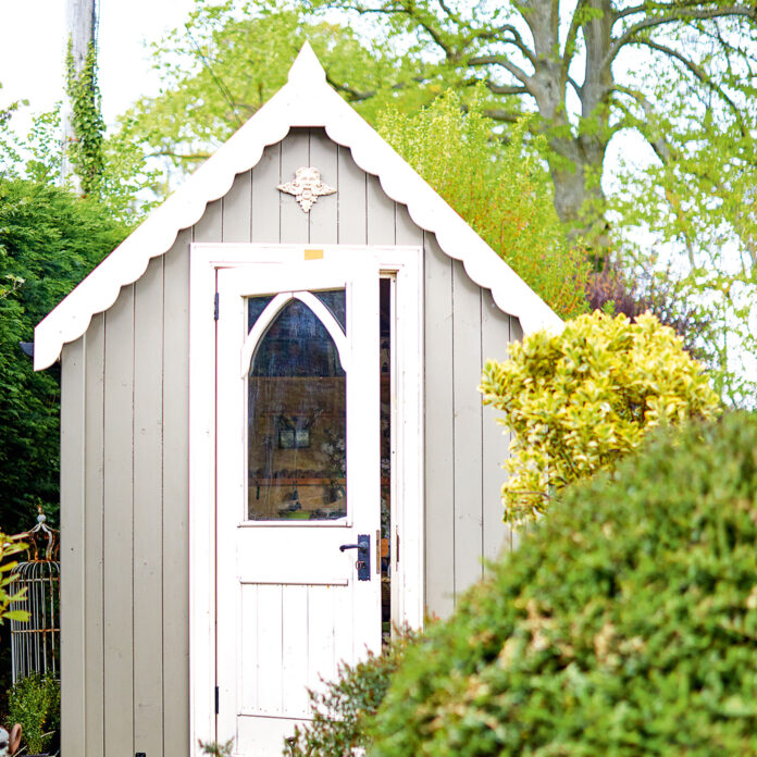 Grey garden shed with white roof and door