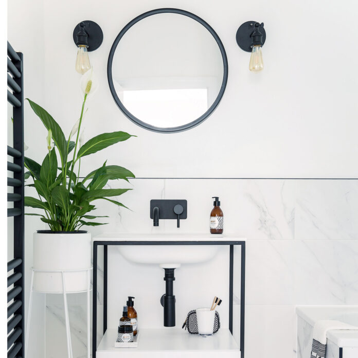 White bathroom with black metal washstand, mirror, lights and towel warmer