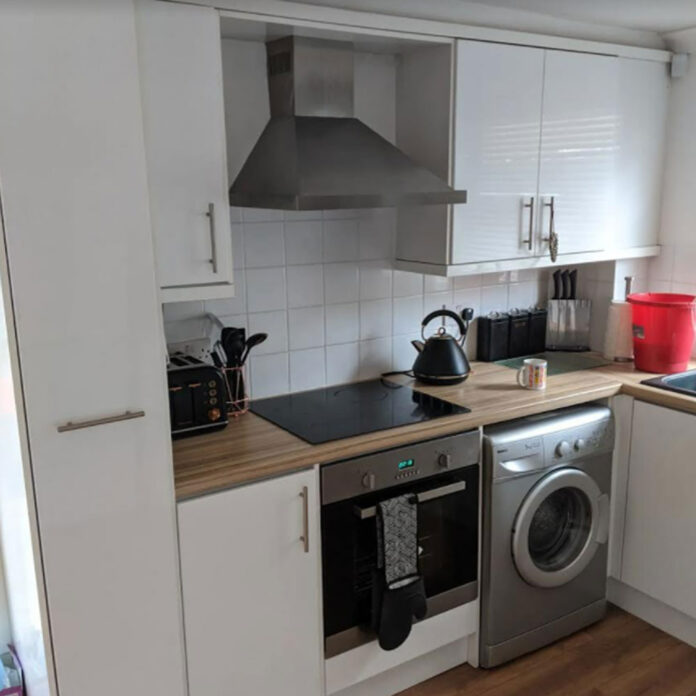 white kitchen with washing machine, hob and wooden worktop