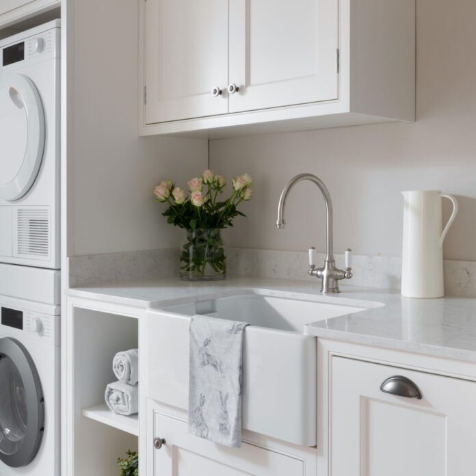 white utiliy room with butler sink and stacked appliances