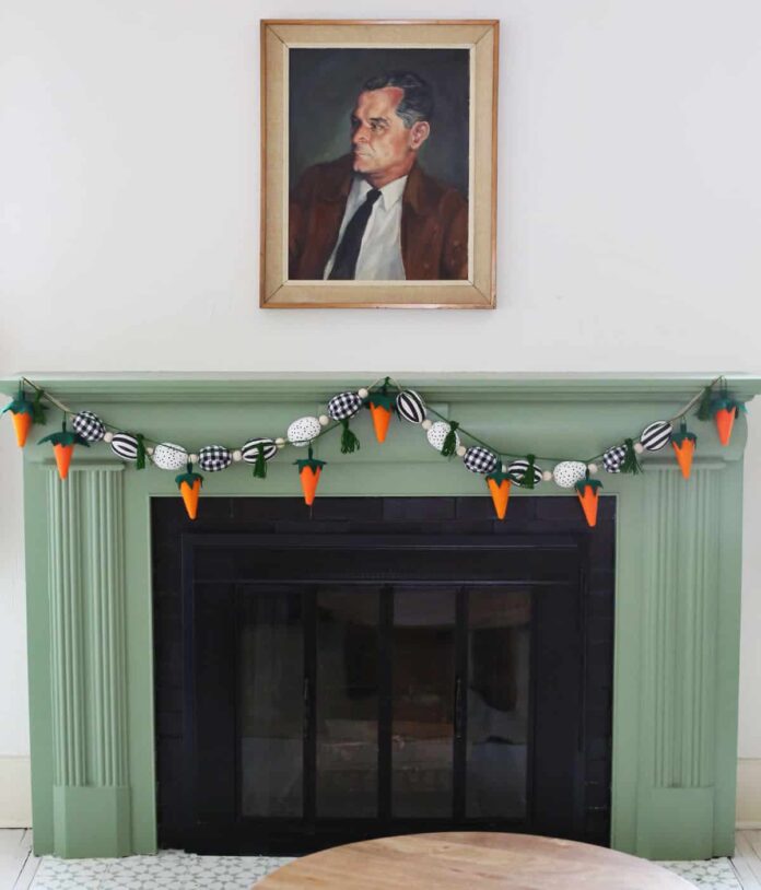 Carrot yarn garland hanging on green fireplace