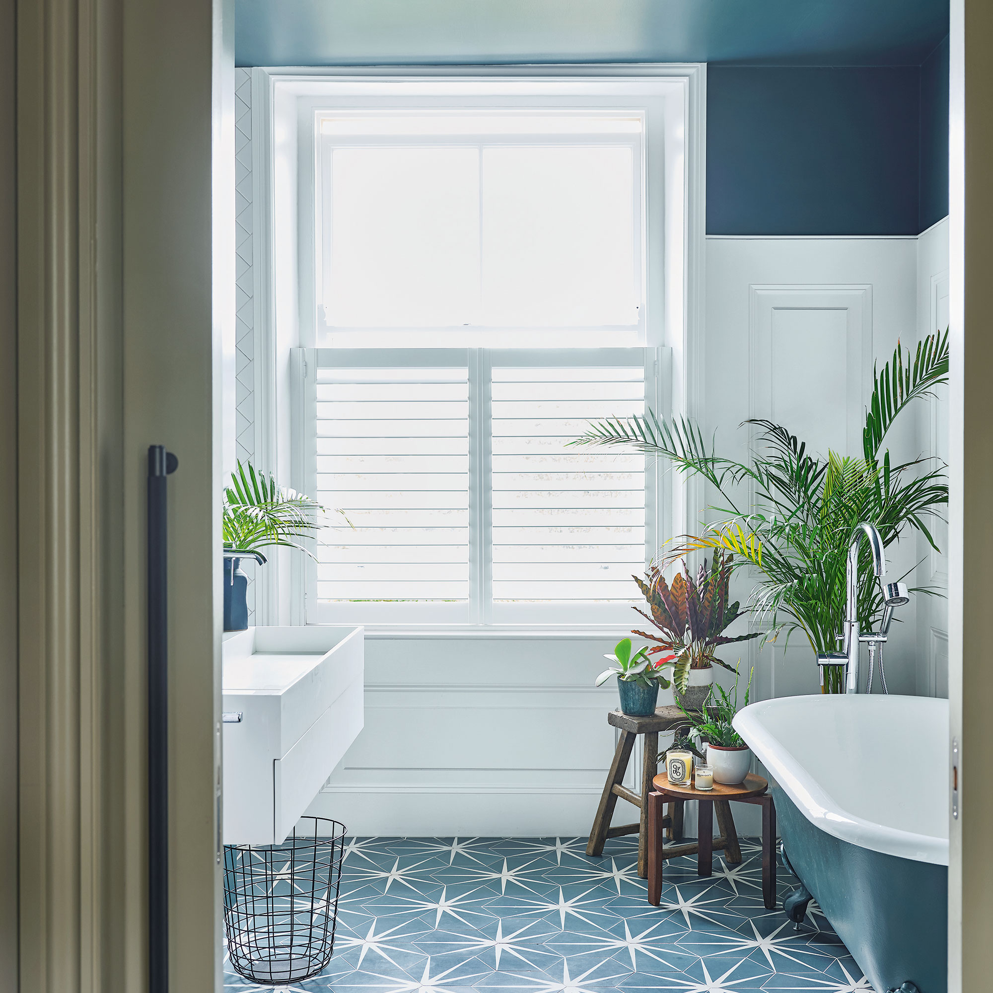 White bathroom with blue painted ceiling and bath, and patterned tile floor