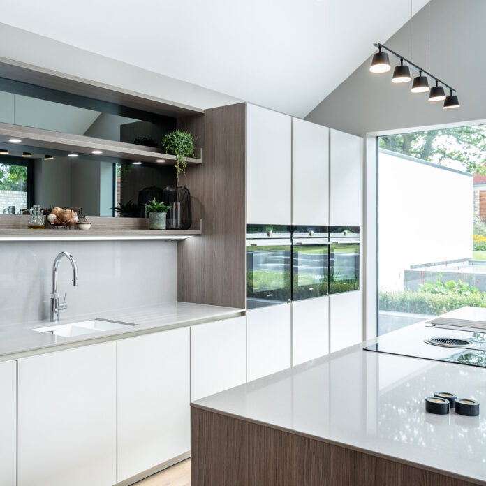 White kitchen with in built appliances and hob on island