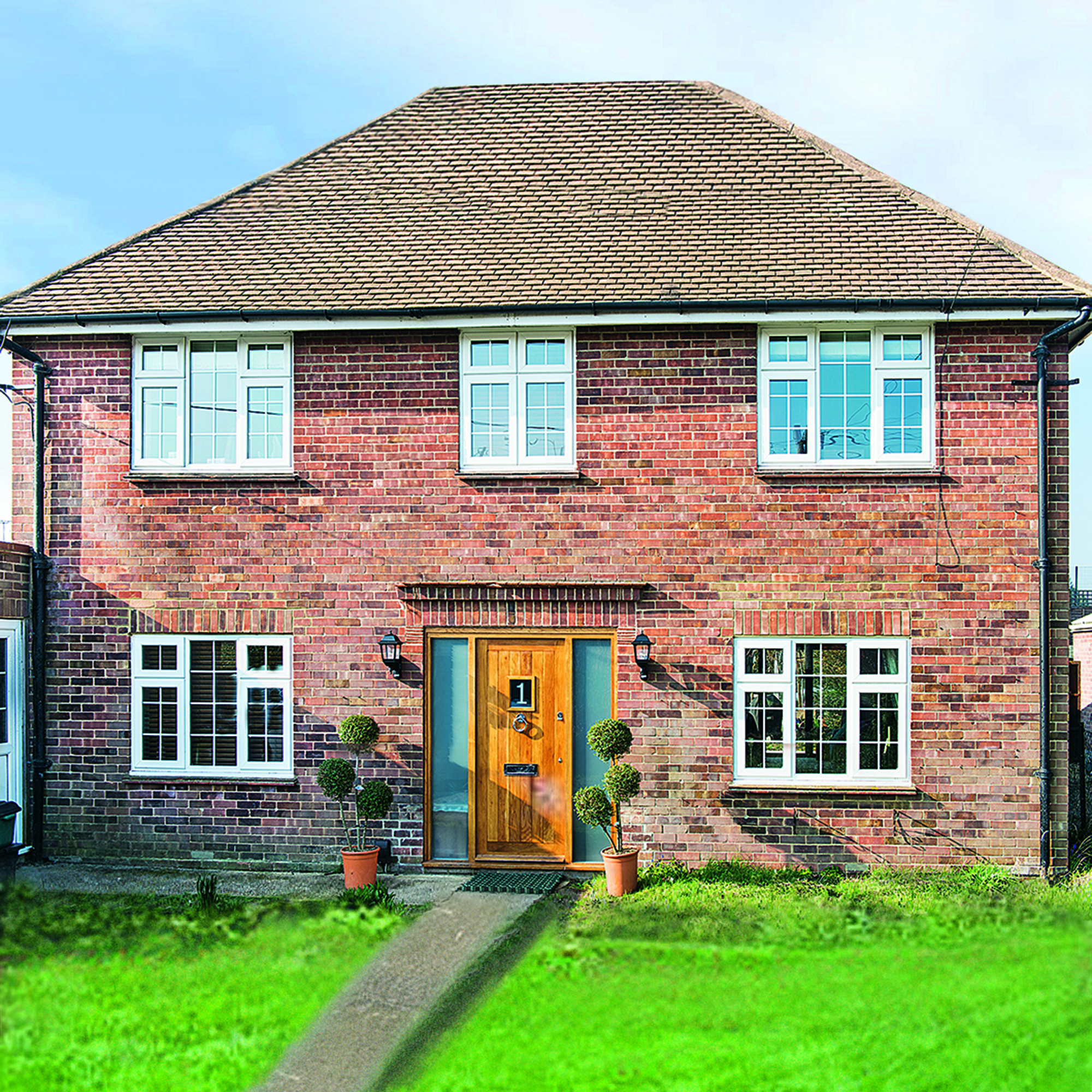 Red brick detached house with front lawn and path, wood front door