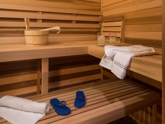 The inside of a home sauna with towels and flip flops on the benches.