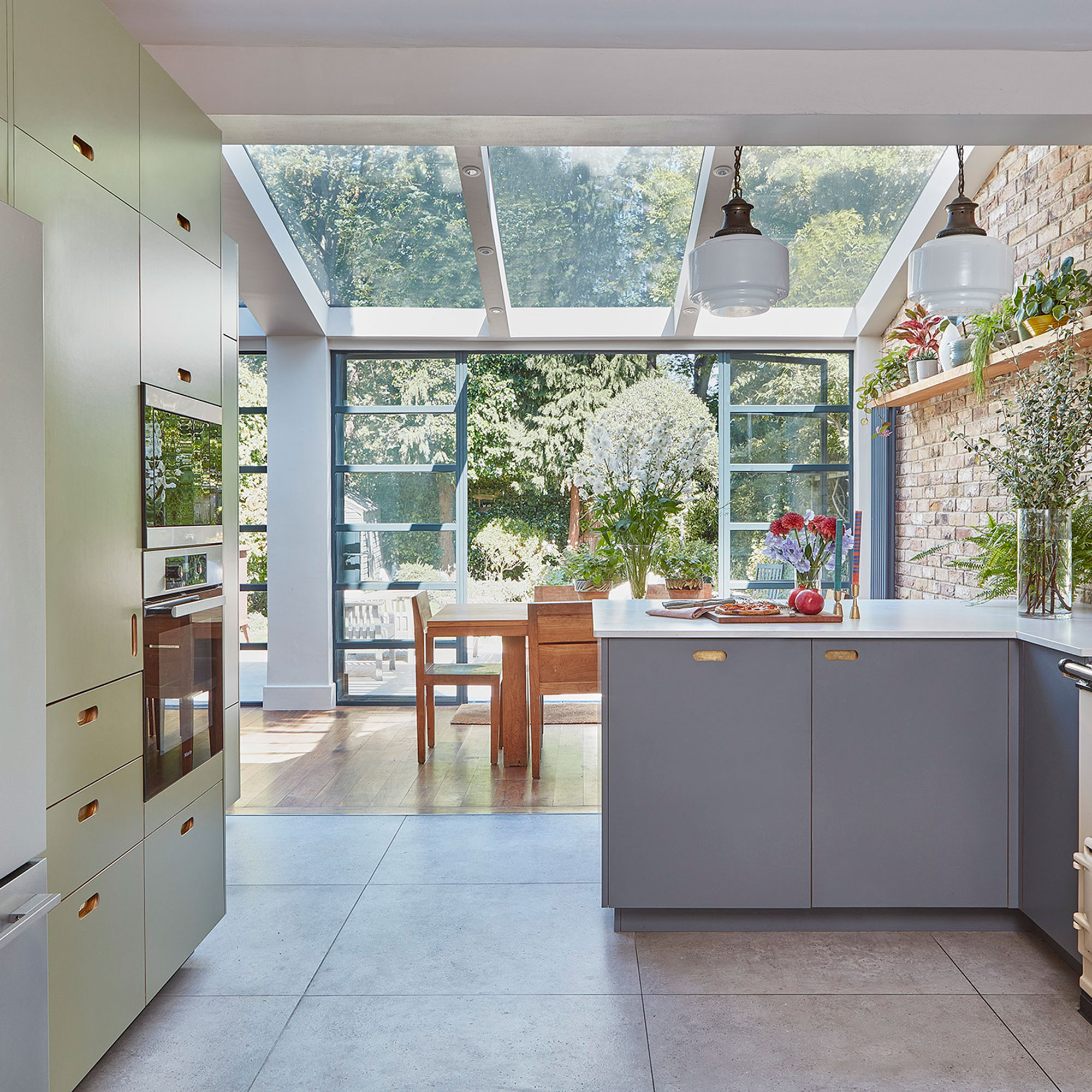 Kitchen with skylight, bifold doors, green cabinets and wooden dining table