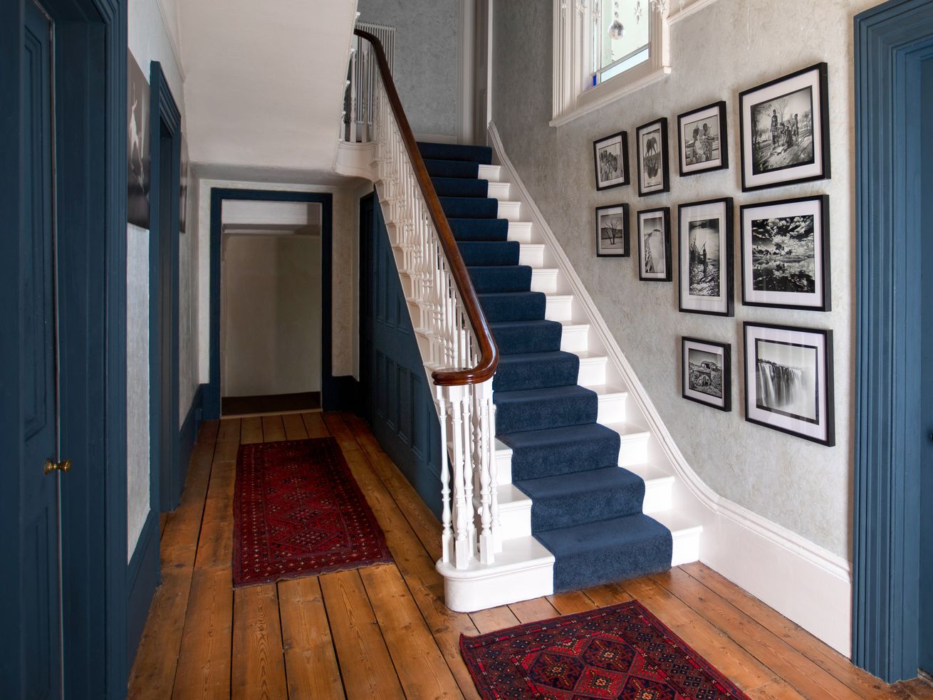 A staircase with a blue runner in an old, traditional  home.