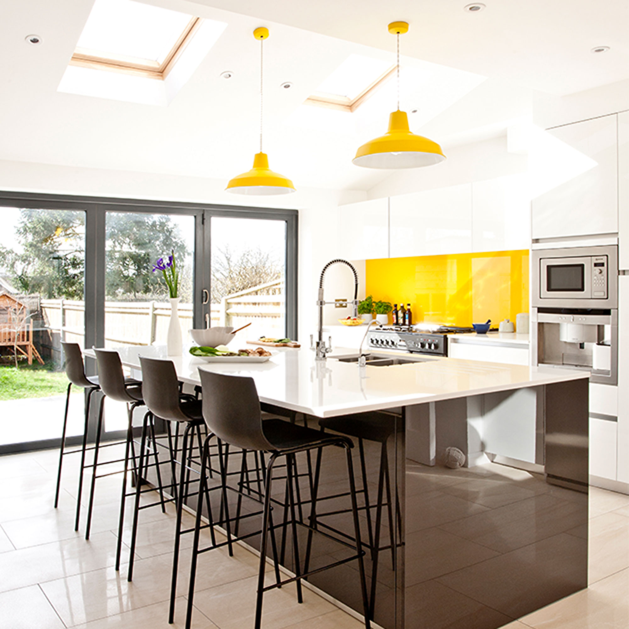 white kitchen with black island and yellow glass splashback
