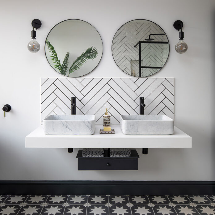 white bathroom with floating vanity and twin basins. Chevron white tiles, twin round mirrors and wall lights