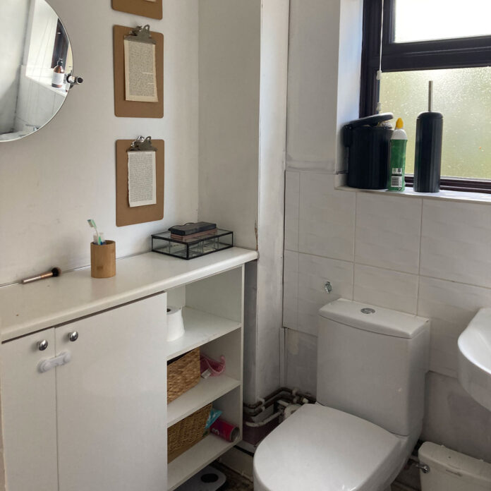 white bathroom with vanity unit, toilet, clipboards, round mirror