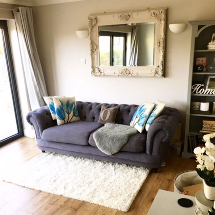 Beige living room with grey sofa, cream rug and ornate mirror