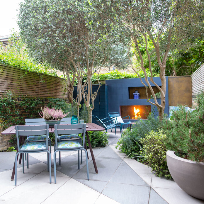 Garden with tiled ground, fireplace in wall and table and chairs