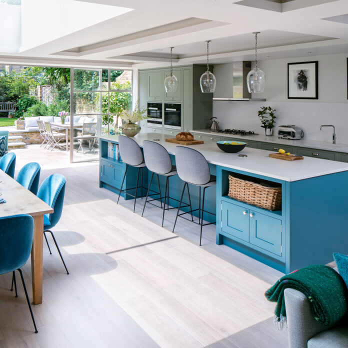 Open plan kitchen with blue island and green cabinetry