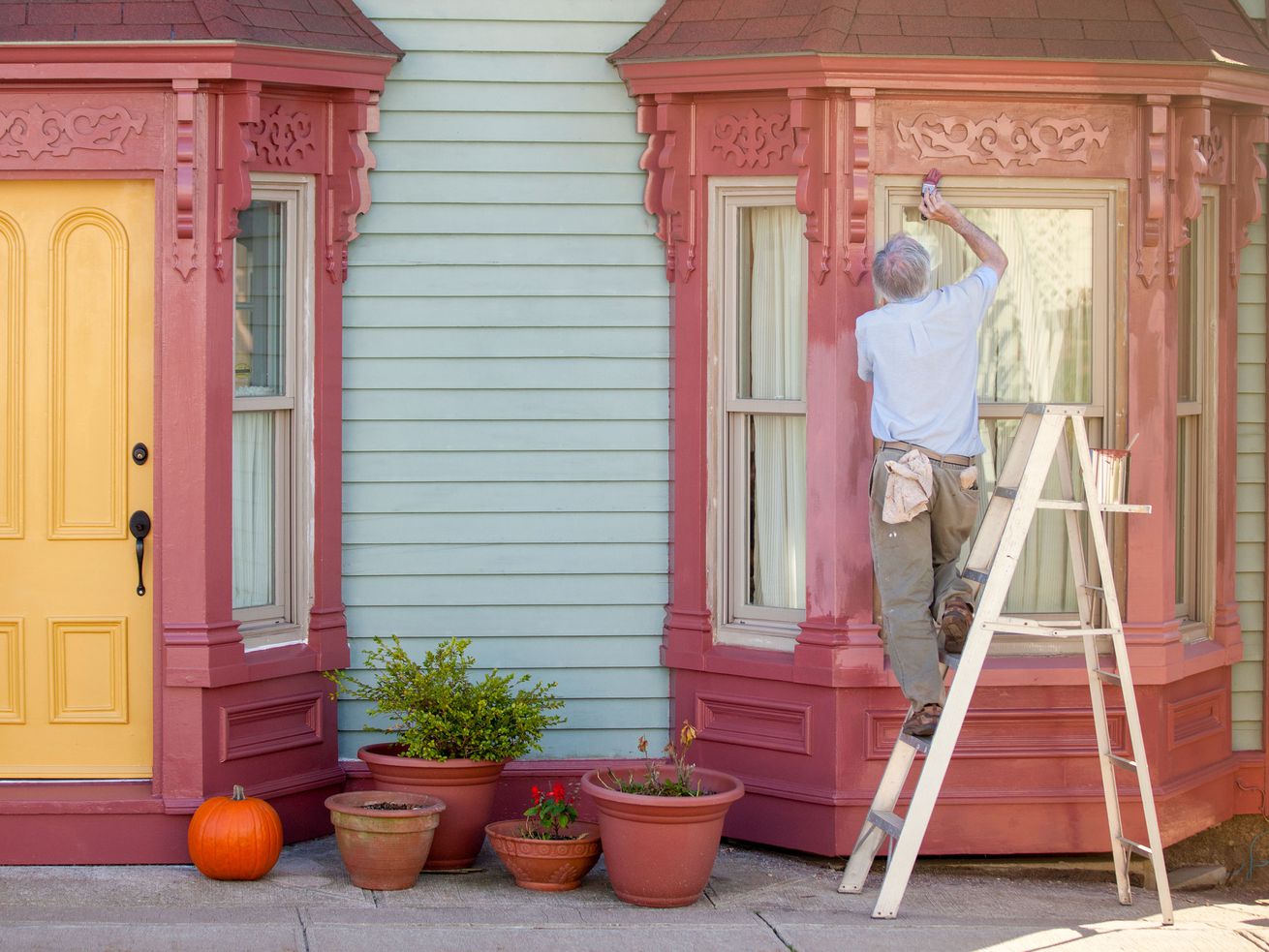 A man painting the outside of a historical home