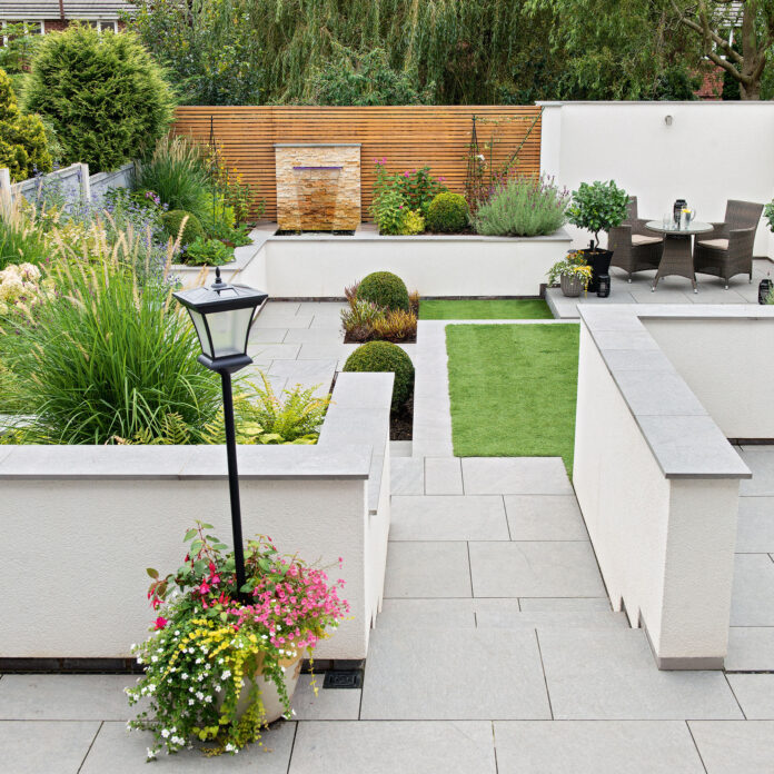 Garden with terraced and lawn areas with water feature on back wall