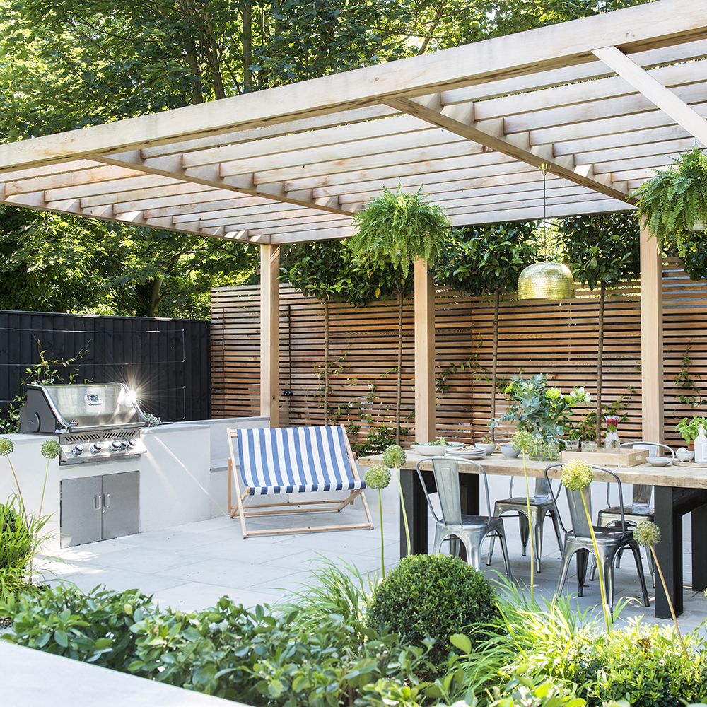 wooden pergola covering an outdoor kitchen and dining table